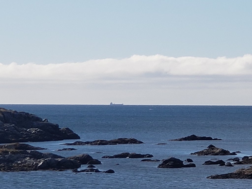 Ship sails on the ocean  as the water touches the sky during a nice summer day