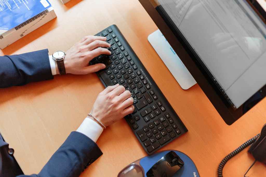Man typing on a keyboard sitting at his desk, on the computer 