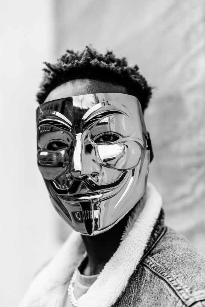 Masked man looks at camera in stock image with a grey, silver texture stock image 