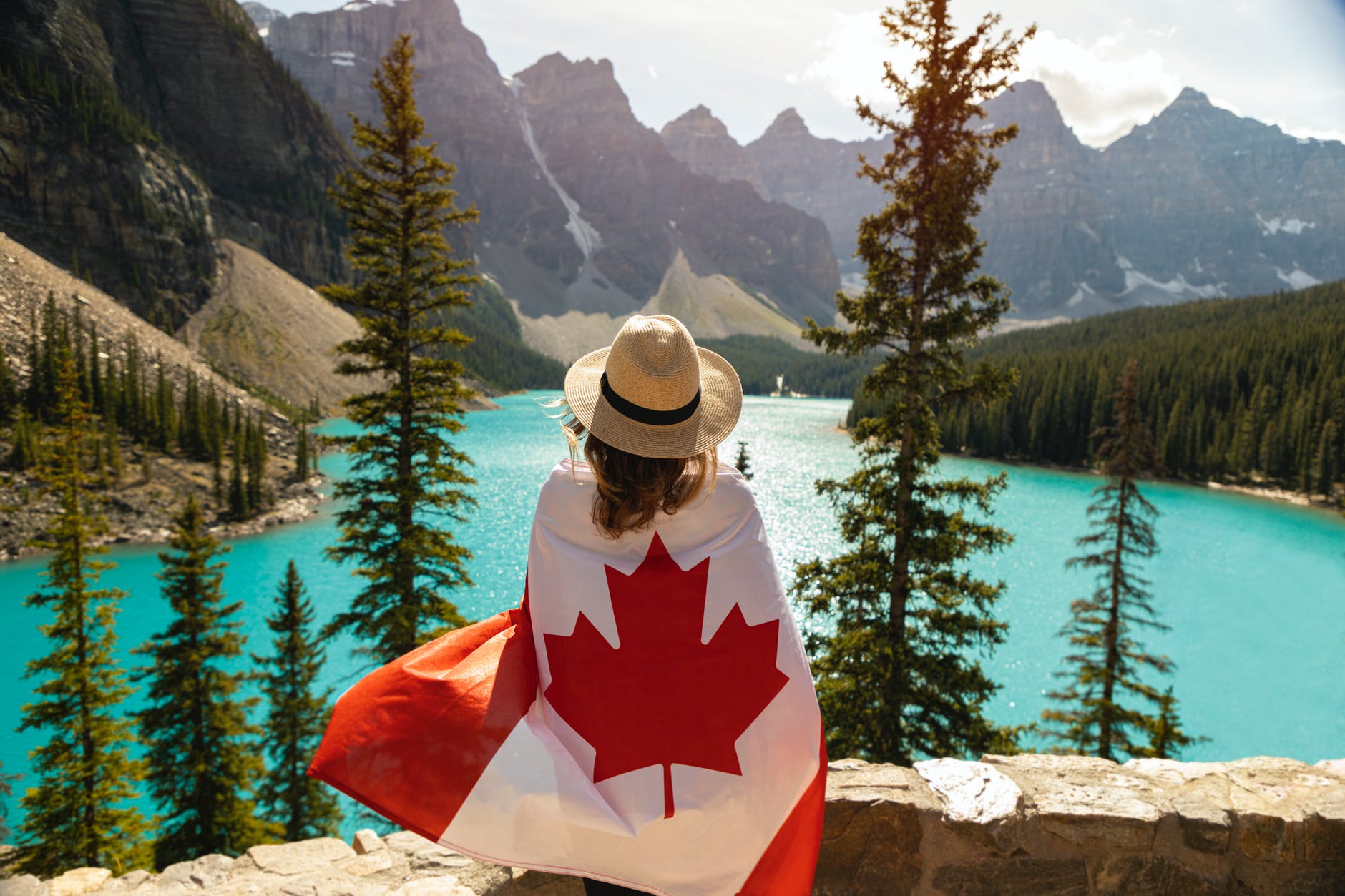 Girl sits back on wrapped in the cool Canadian Flag as the scenery is beautiful in the background 